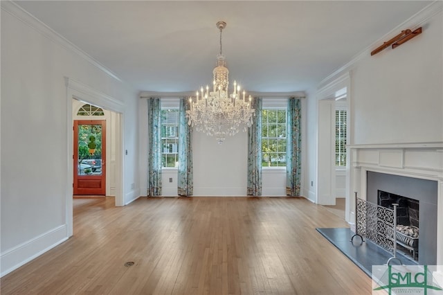 interior space with an inviting chandelier, light hardwood / wood-style floors, and ornamental molding