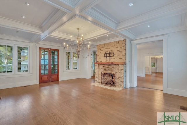 unfurnished living room with a wealth of natural light, hardwood / wood-style flooring, a chandelier, and a fireplace