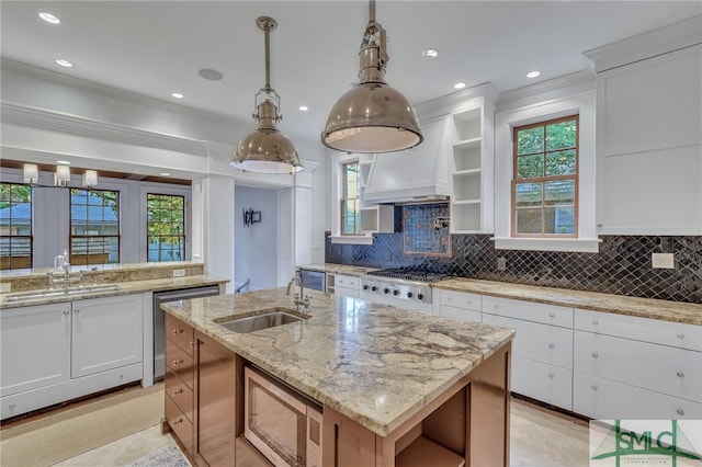 kitchen with white cabinetry, stainless steel appliances, sink, and a center island with sink