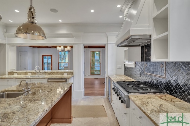 kitchen featuring white cabinetry, premium range hood, sink, and hanging light fixtures