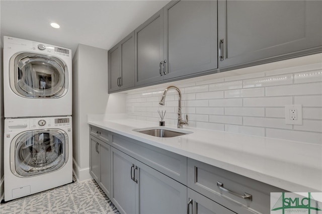 washroom with stacked washing maching and dryer, cabinets, and sink