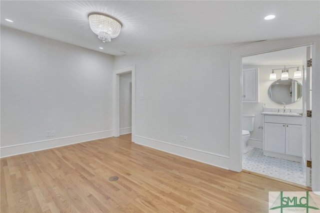 unfurnished bedroom featuring ensuite bath, sink, and light wood-type flooring