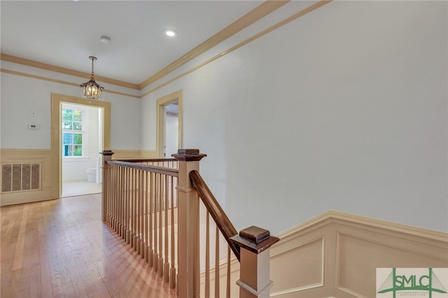 hallway featuring crown molding, a notable chandelier, and wood-type flooring