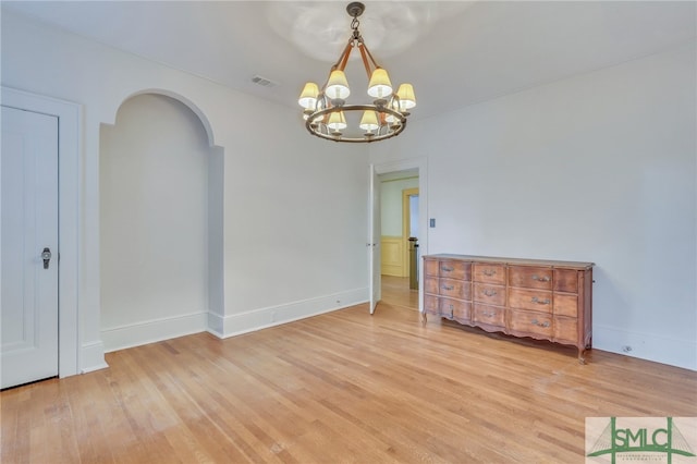 spare room featuring a chandelier and light hardwood / wood-style floors