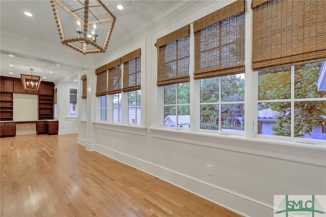 interior space with wood-type flooring, ornamental molding, a chandelier, and vaulted ceiling