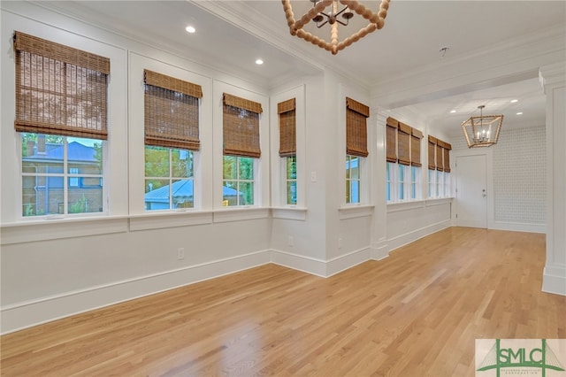 unfurnished room with crown molding, hardwood / wood-style floors, and an inviting chandelier