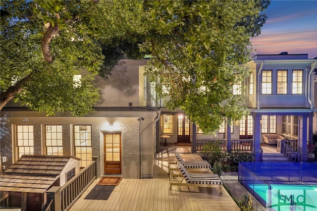 back house at dusk with a swimming pool side deck