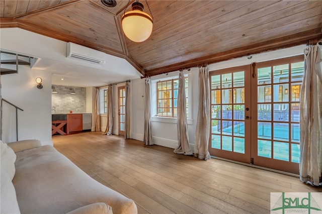 unfurnished living room featuring lofted ceiling, a wall mounted AC, light wood-type flooring, and french doors