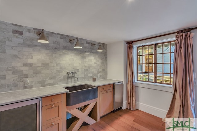 interior space featuring light wood-type flooring, tasteful backsplash, dishwasher, beverage cooler, and sink