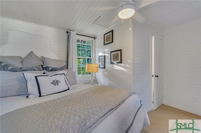 carpeted bedroom featuring ceiling fan and wooden walls