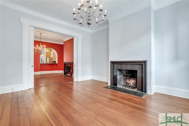 unfurnished living room with an inviting chandelier, ornamental molding, and hardwood / wood-style flooring