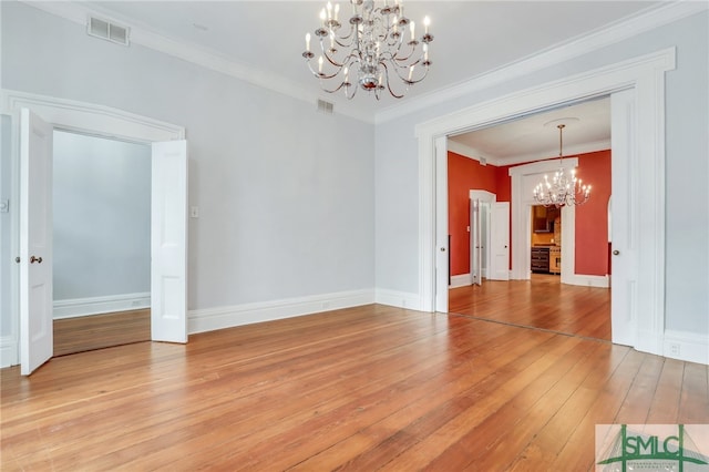 unfurnished room featuring an inviting chandelier, light wood-type flooring, and crown molding