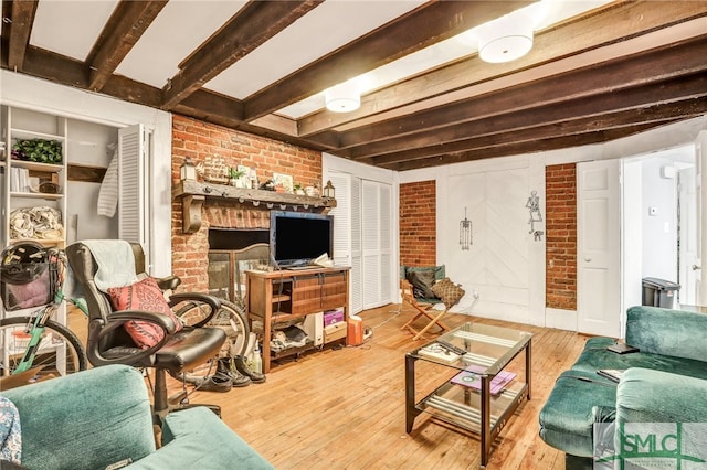 living room featuring brick wall, beamed ceiling, and light hardwood / wood-style flooring