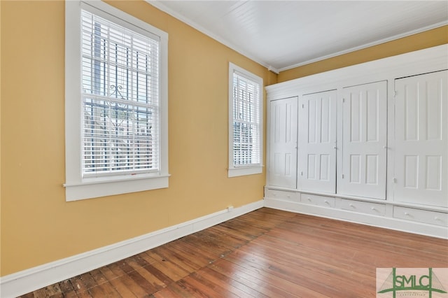 unfurnished bedroom featuring multiple closets, hardwood / wood-style flooring, and multiple windows