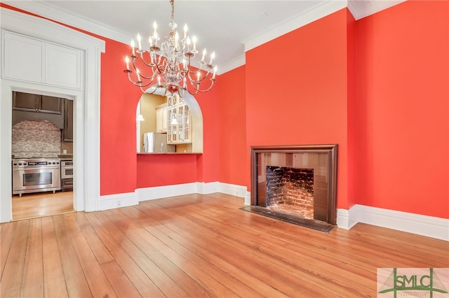 unfurnished living room with crown molding, an inviting chandelier, and hardwood / wood-style floors