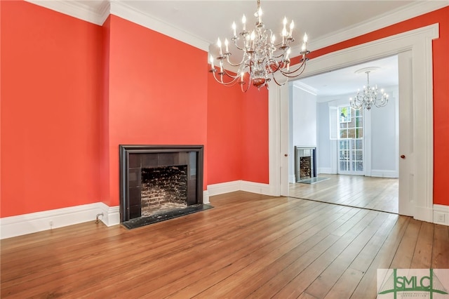 unfurnished living room featuring hardwood / wood-style floors, a chandelier, and ornamental molding