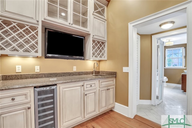 kitchen featuring wine cooler, light stone countertops, light tile flooring, sink, and cream cabinetry