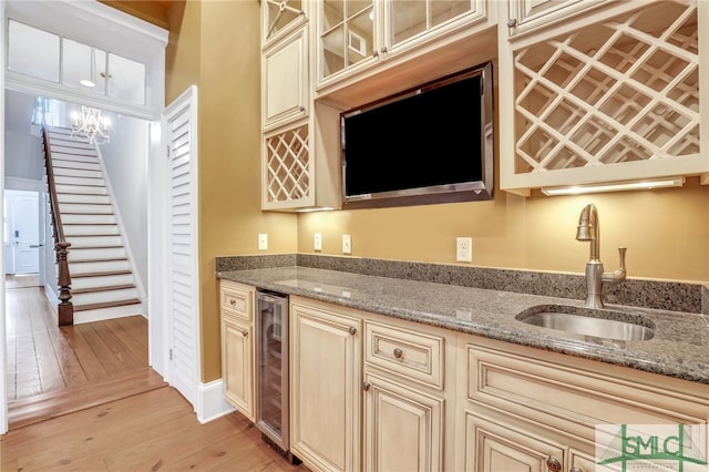 kitchen featuring light stone countertops, cream cabinetry, light hardwood / wood-style floors, and beverage cooler