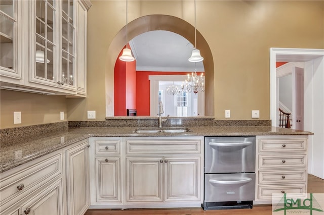 kitchen featuring stainless steel dishwasher, wood-type flooring, hanging light fixtures, sink, and a chandelier