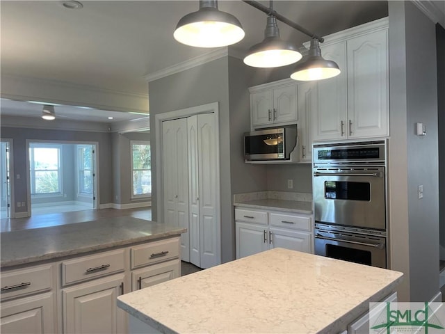 kitchen featuring appliances with stainless steel finishes, decorative light fixtures, a kitchen island, and white cabinets