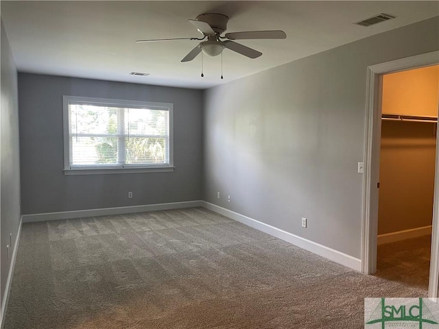 unfurnished bedroom featuring a spacious closet, a closet, ceiling fan, and carpet flooring