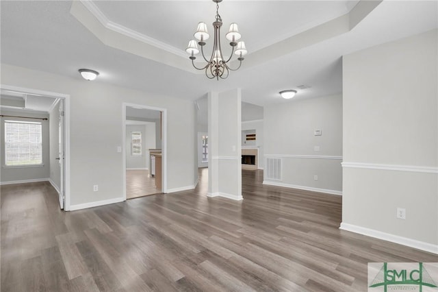 interior space with a fireplace, a raised ceiling, baseboards, and wood finished floors