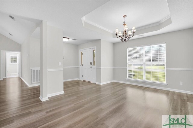 spare room featuring a raised ceiling, hardwood / wood-style floors, and a chandelier