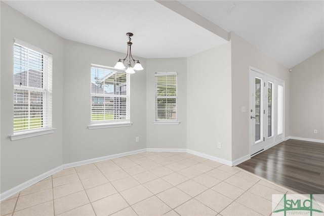 unfurnished dining area featuring baseboards, an inviting chandelier, and wood finished floors