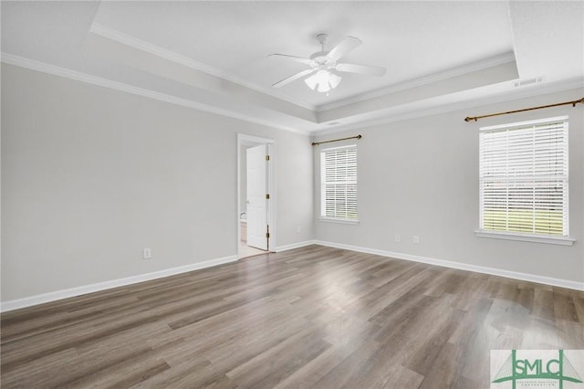 spare room featuring ornamental molding, a tray ceiling, wood finished floors, baseboards, and ceiling fan