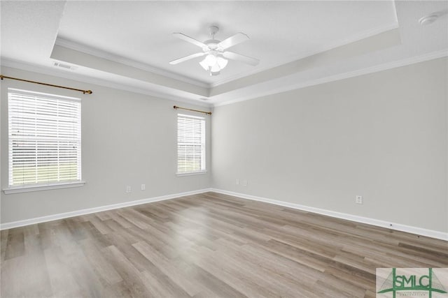 empty room featuring visible vents, a raised ceiling, wood finished floors, and a ceiling fan