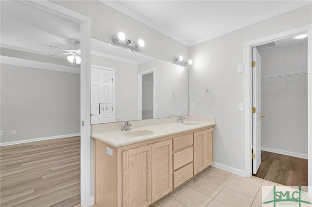 bathroom with ceiling fan, double sink vanity, crown molding, and wood-type flooring