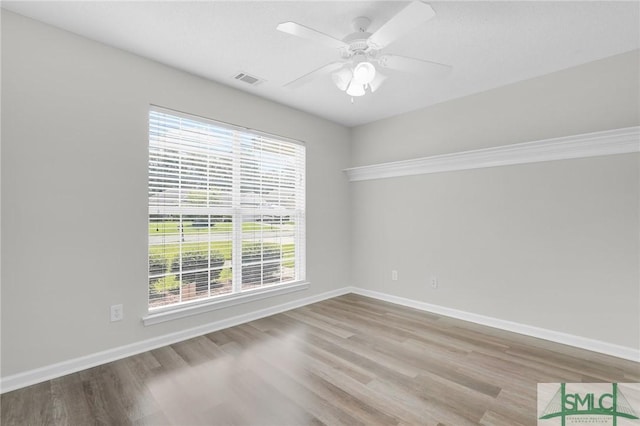 empty room featuring wood finished floors, baseboards, and ceiling fan