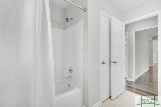 bathroom with baseboards, shower / bath combo with shower curtain, and tile patterned flooring