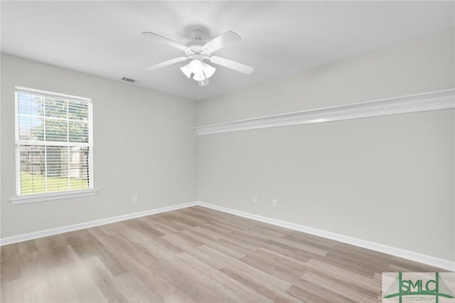 empty room featuring baseboards, visible vents, a ceiling fan, and light wood-style floors