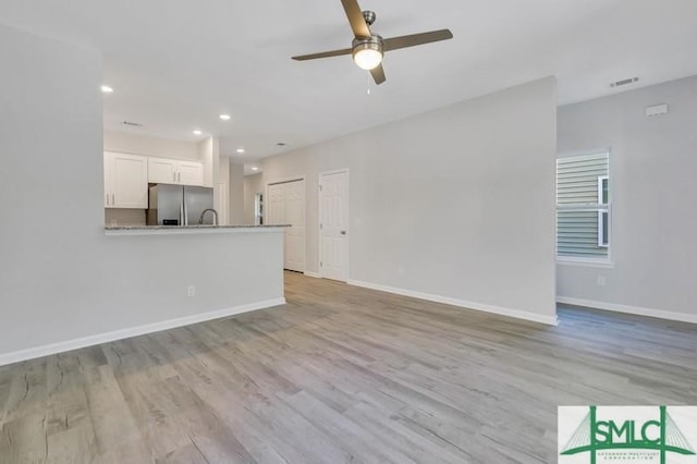 unfurnished living room with ceiling fan, light hardwood / wood-style flooring, and sink