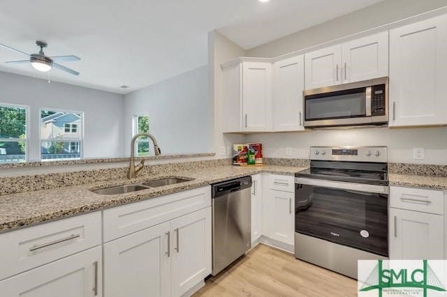 kitchen with light stone counters, light hardwood / wood-style floors, sink, white cabinetry, and stainless steel appliances