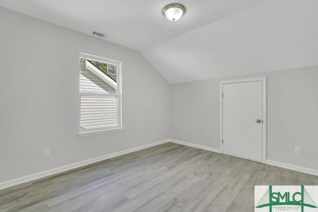 additional living space with vaulted ceiling and light hardwood / wood-style flooring