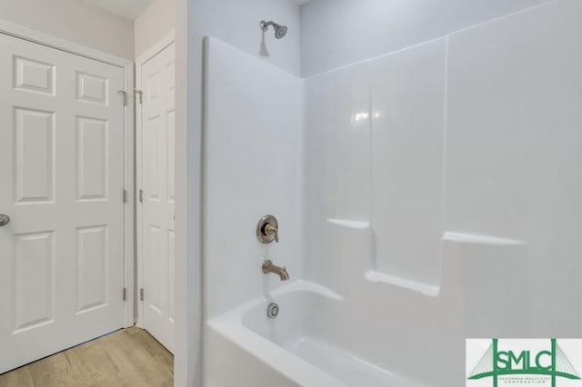 bathroom featuring washtub / shower combination and wood-type flooring