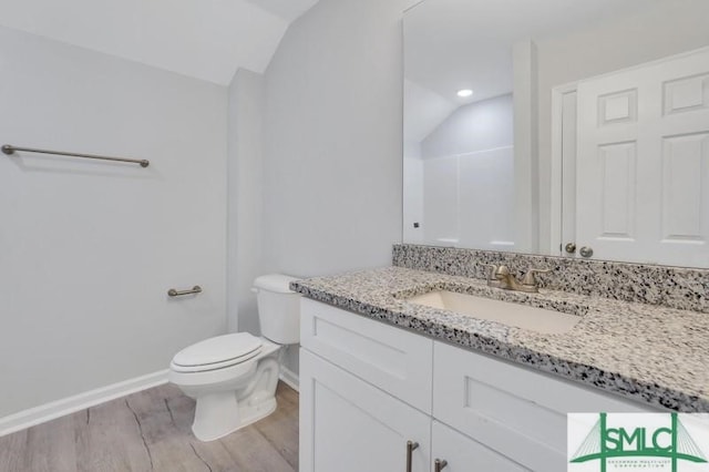 bathroom with vaulted ceiling, vanity, toilet, and hardwood / wood-style flooring