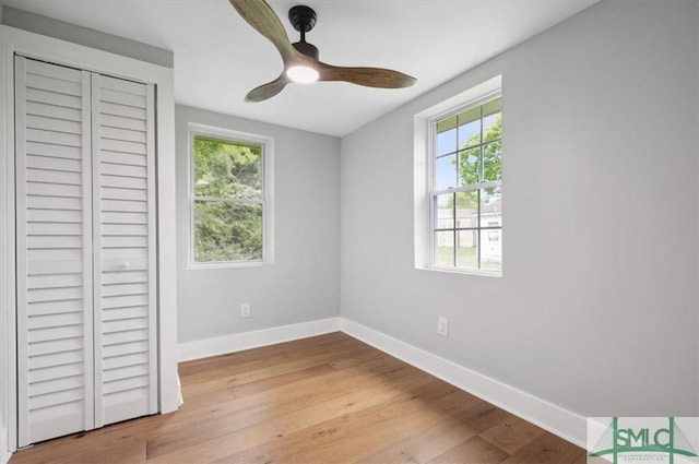 unfurnished bedroom featuring multiple windows, ceiling fan, a closet, and light hardwood / wood-style floors