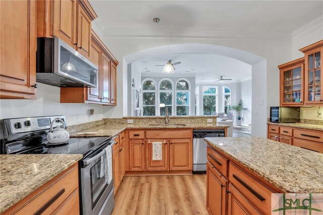 kitchen with light stone countertops, stainless steel appliances, crown molding, sink, and light hardwood / wood-style floors