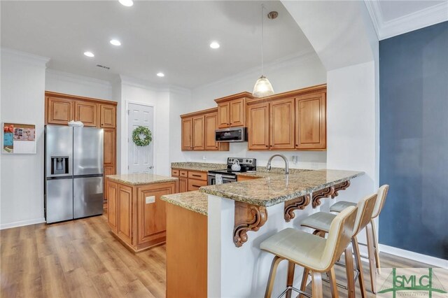 kitchen featuring light stone countertops, hanging light fixtures, stainless steel appliances, light hardwood / wood-style flooring, and kitchen peninsula