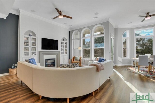 living room featuring dark hardwood / wood-style floors, ceiling fan, and ornamental molding