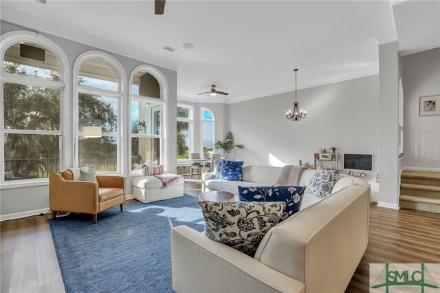 living room featuring ceiling fan with notable chandelier, ornamental molding, and dark wood-type flooring