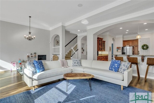 living room featuring hardwood / wood-style floors, ornamental molding, and a chandelier