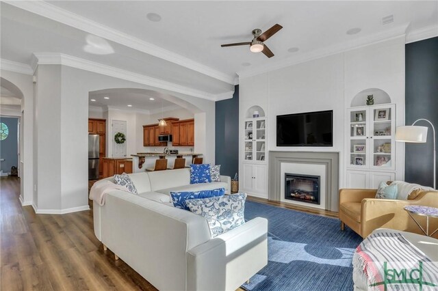 living room with ceiling fan, dark hardwood / wood-style flooring, and ornamental molding