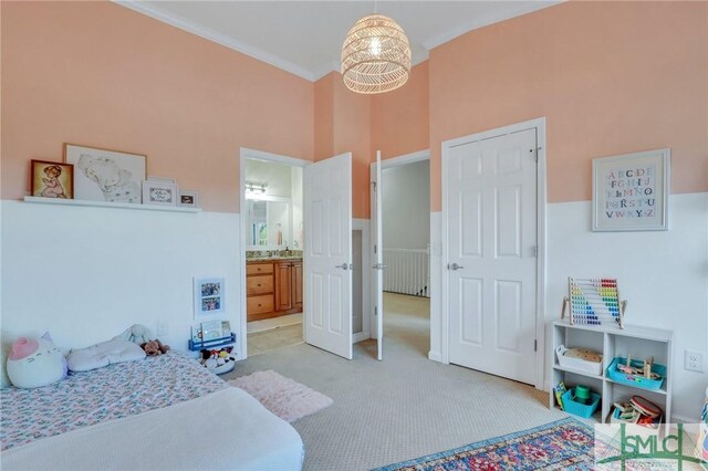 carpeted bedroom with ensuite bath, a high ceiling, and ornamental molding