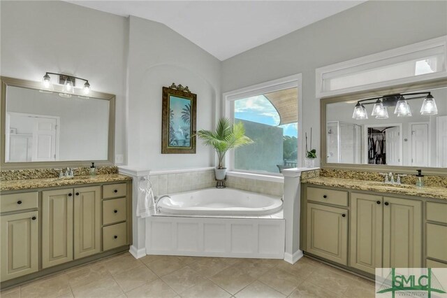 bathroom with tile patterned floors, a washtub, vanity, and lofted ceiling