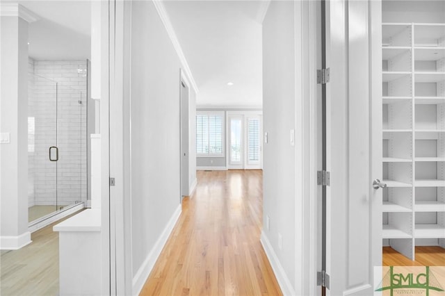 corridor with light hardwood / wood-style floors and ornamental molding