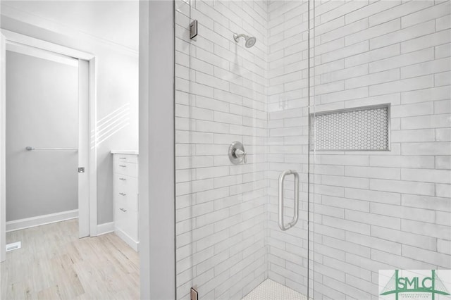 bathroom featuring hardwood / wood-style flooring, ornamental molding, and walk in shower